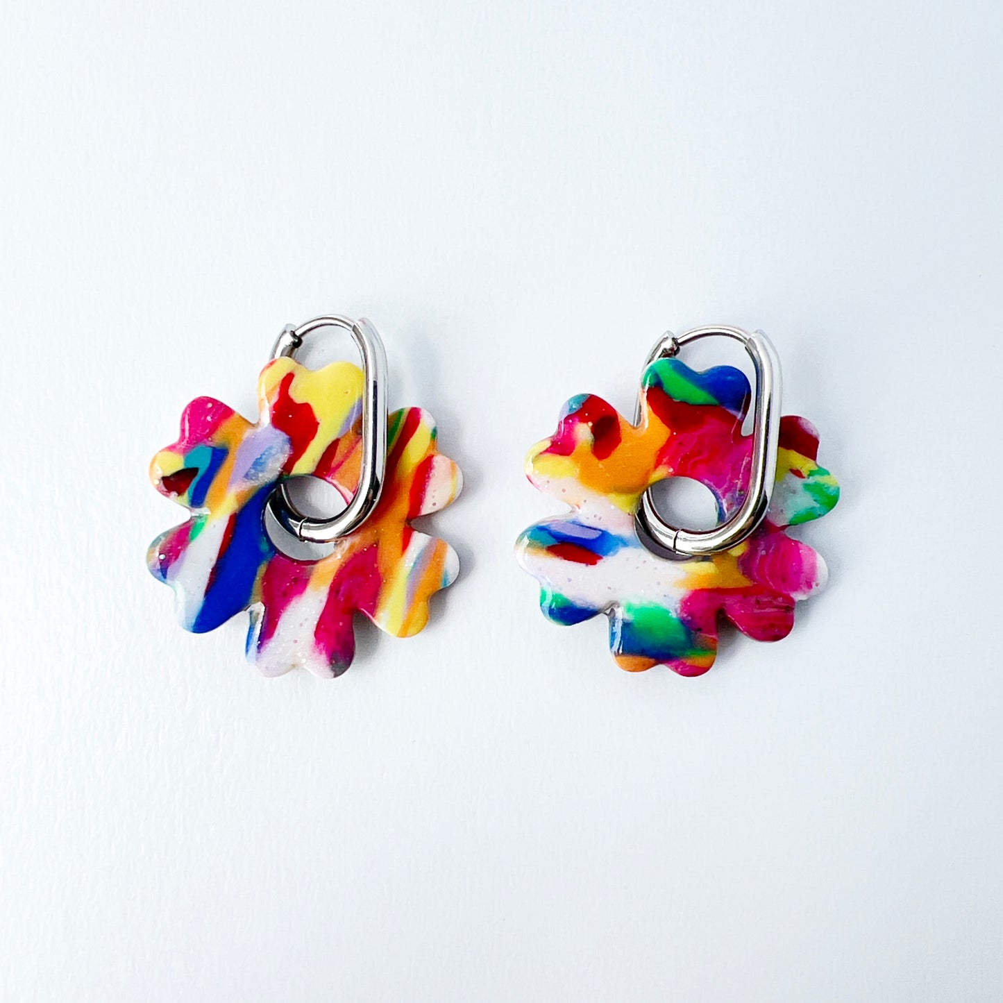 Colorful flower-shaped earrings with 316L surgical stainless steel oval hoops on a white background