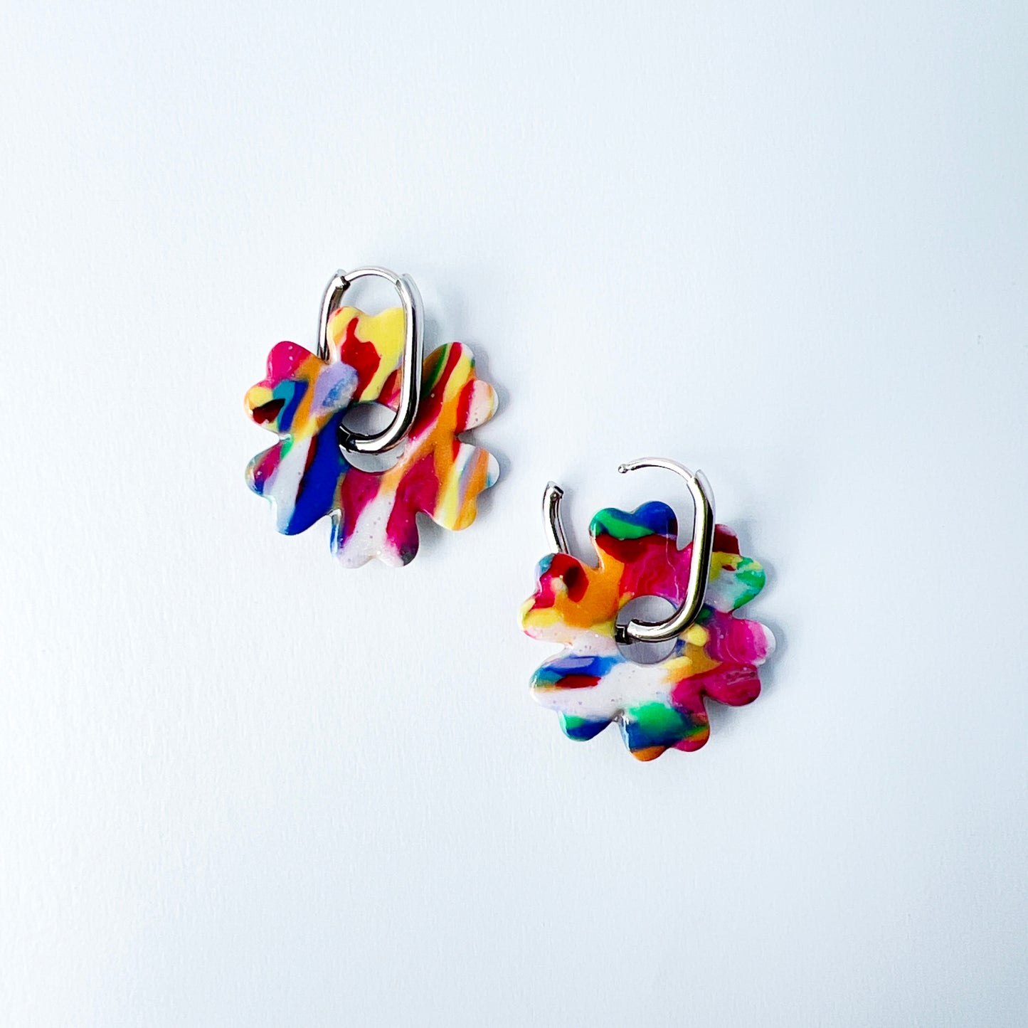 Colorful flower-shaped earrings with 316L surgical stainless steel oval hoops on a white background