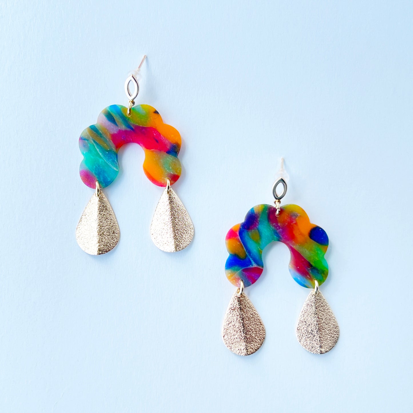 Bold handmade earrings with abstract rainbow swirl polymer clay tops in a semi-translucent finish, featuring glitter-textured gold teardrop dangles and 18K gold-plated brass oval stud posts