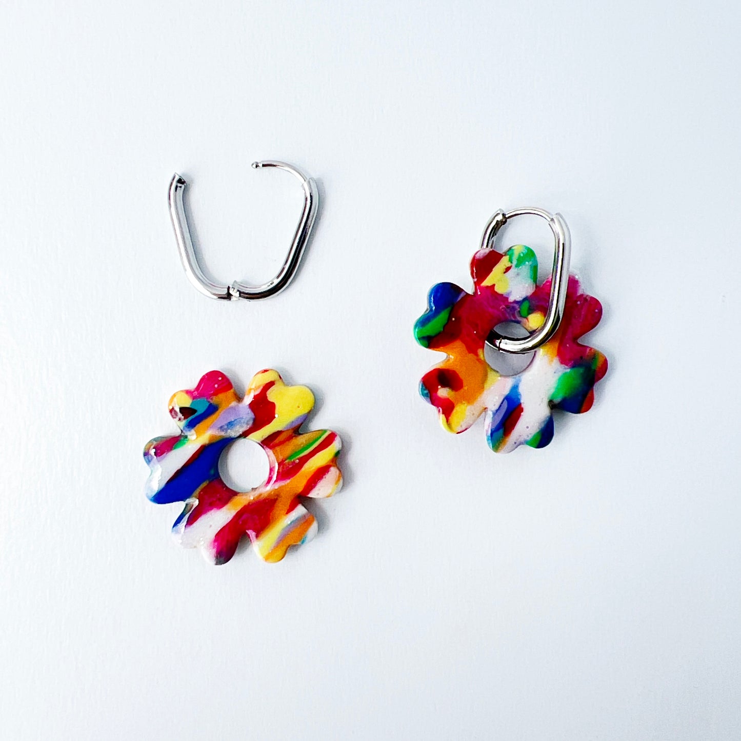 Colorful flower-shaped earrings with 316L surgical stainless steel oval hoops on a white background