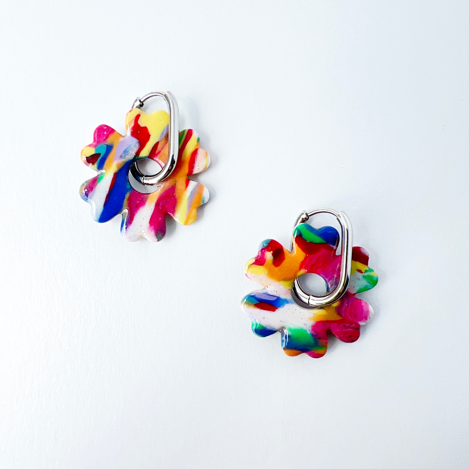 Colorful flower-shaped earrings with 316L surgical stainless steel oval hoops on a white background