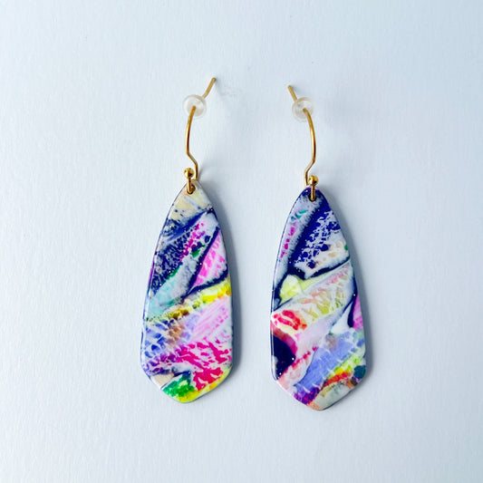 Asymmetrical dagger-shaped earrings made of polymer clay with vibrant marbling that looks like abrushstroke patterns in rainbow colors. Hanging on gold stainless steel earwires.