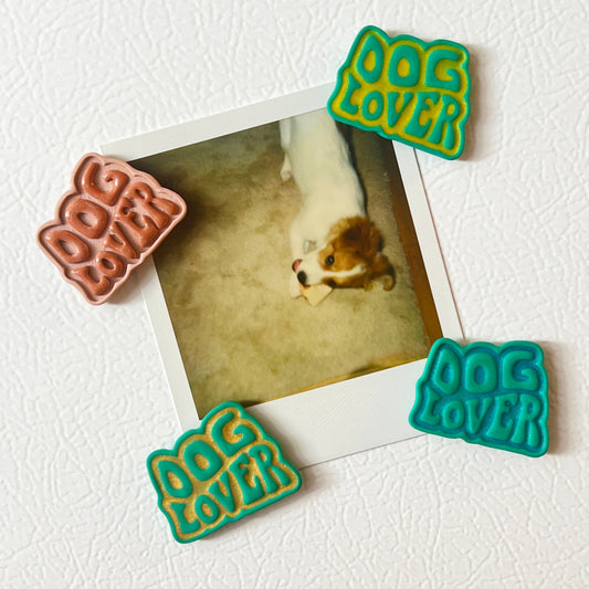 Four 'Dog Lover' magnets on a white surface with a photo of a dog.