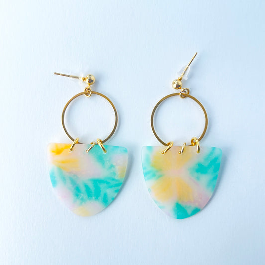 A pair of handmade earrings featuring semi-transparent polymer clay shields with soft pastel patterns of yellow butterflies and green leaves, attached to gold-plated hoops and ball posts.