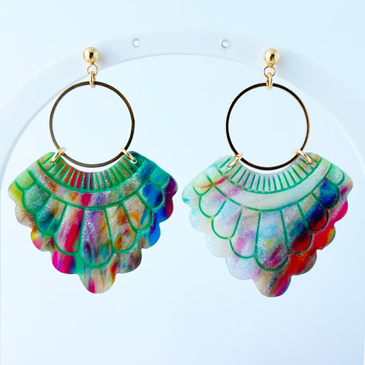 A pair of handmade fan-shaped polymer clay earrings displayed on a white background. The earrings feature gold-plated ball posts and hoops, with semi-transparent rainbow-colored clay and green etched fan-like lines. The marbling effect shows swirls of pink, blue, green, orange, and white.